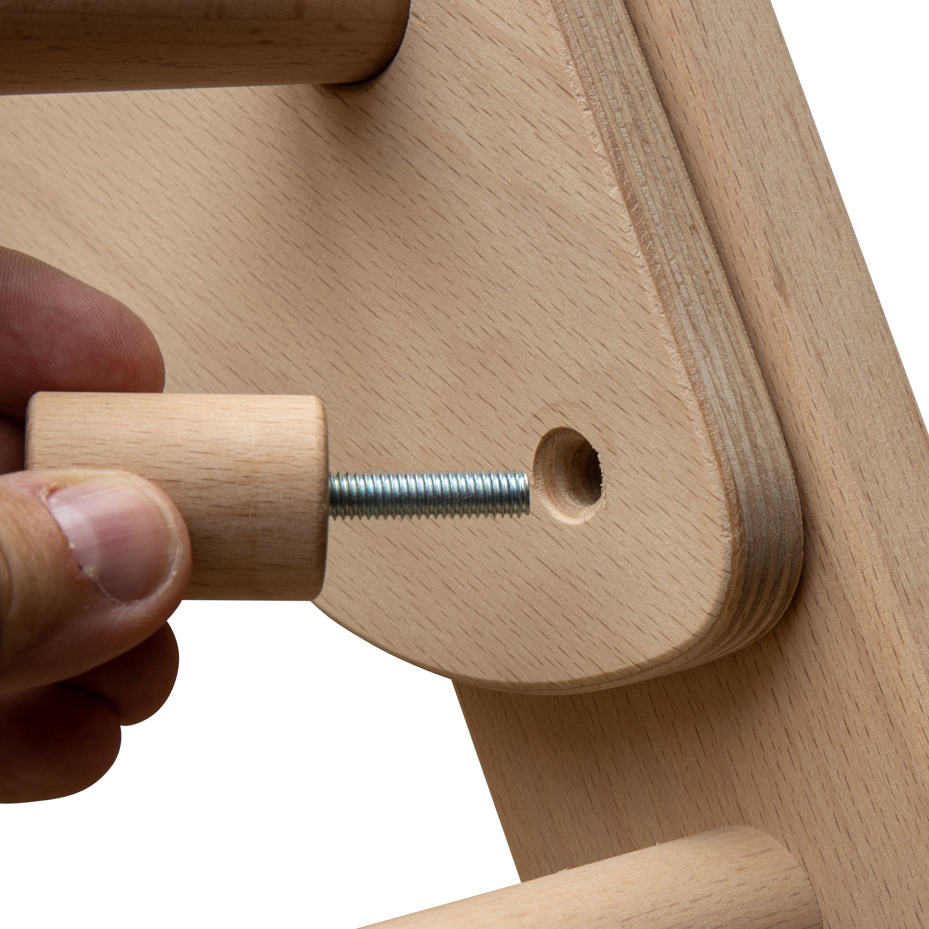 Nahaufnahme eines Kletterdreiecks aus Holz, bei dem eine Hand eine Schraube in eine dafür vorgesehene Bohrung dreht, um die Kindersicherung zu befestigen.